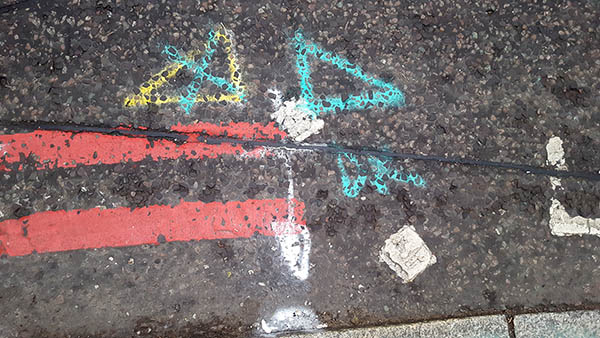 Pavement markings - spray painted squiggles on paving stones - Green yellow and white markings