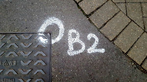Pavement markings - spray painted squiggles on paving stones - White letters O B 2