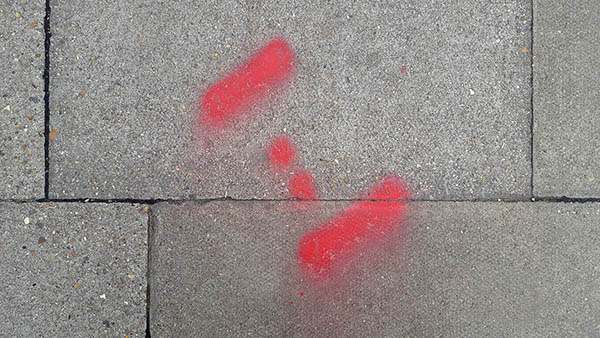 Pavement markings - spray painted squiggles on paving stones - Red dots flanked by lines
