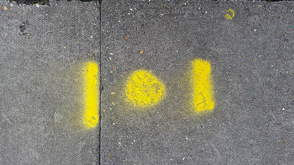 Pavement markings - spray painted squiggles on paving stones - Yellow dot flanked by lines