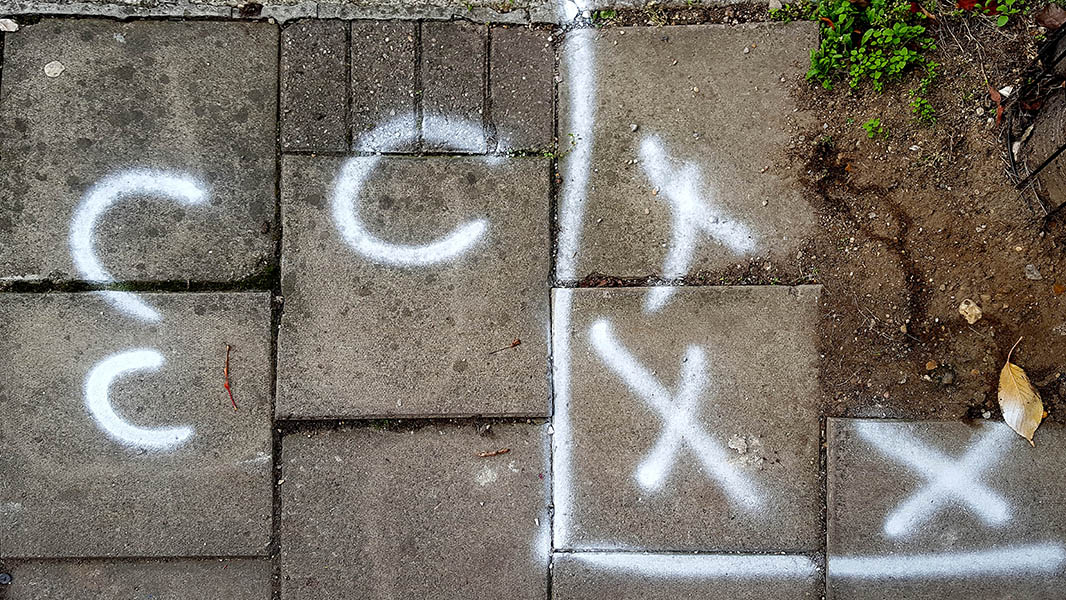 Pavement markings - spray painted squiggles on paving stones - Three white C's on the left with three X's to the right separated by vertical line