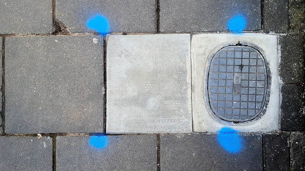 Pavement markings - spray painted squiggles on paving stones - Small access panel surrounded by four blue dots forming a square