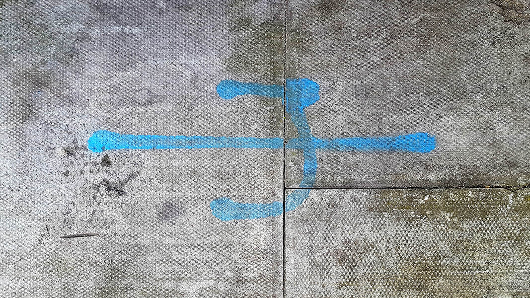 Pavement markings - spray painted squiggles on paving stones - Blue horizontal line with a backwards C in the centre