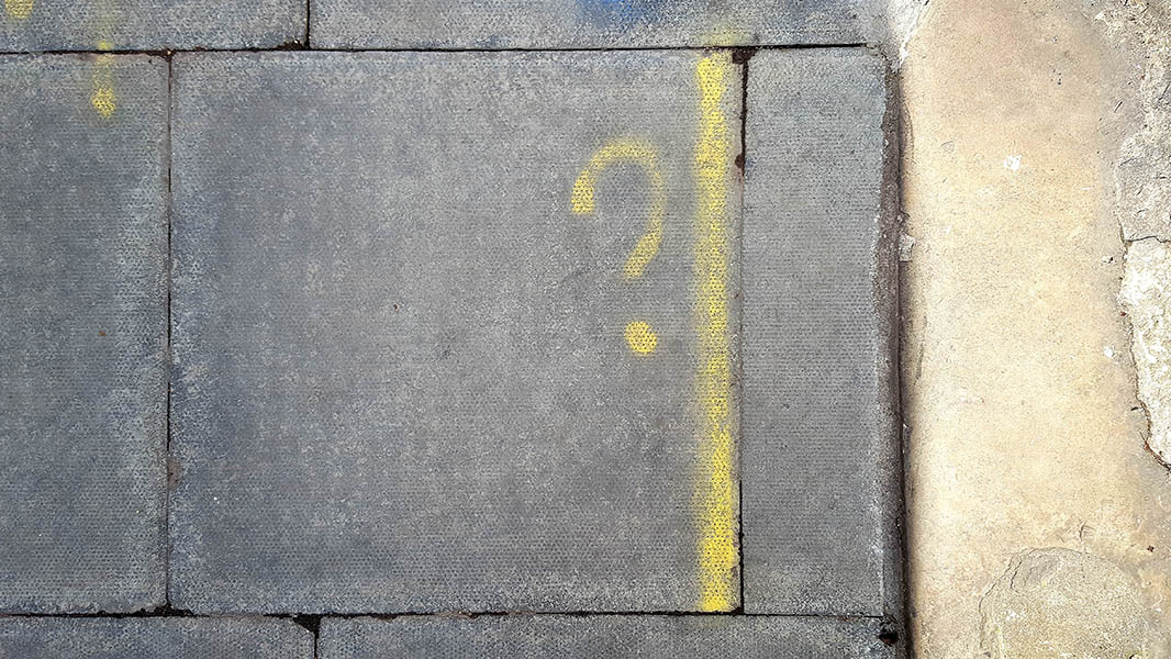 Pavement markings - spray painted squiggles on paving stones - Yellow question mark with vertical line to the right