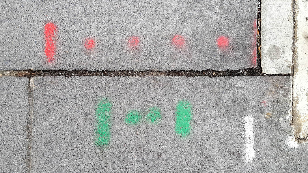 Pavement markings - spray painted squiggles on paving stones - Four red dots flanked by vertical lines above two green dots flanked by vertical lines