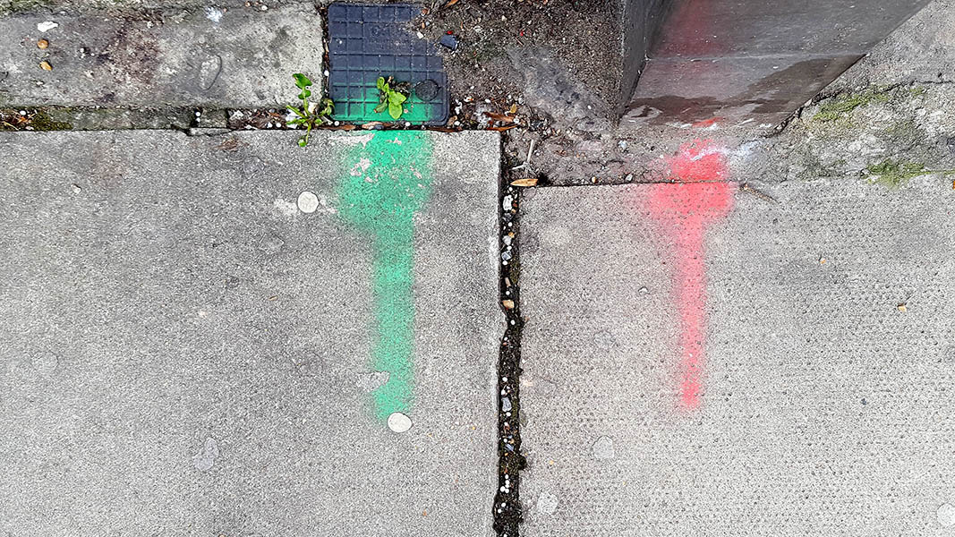 Pavement markings - spray painted squiggles on paving stones - Green and red arrow pointing up