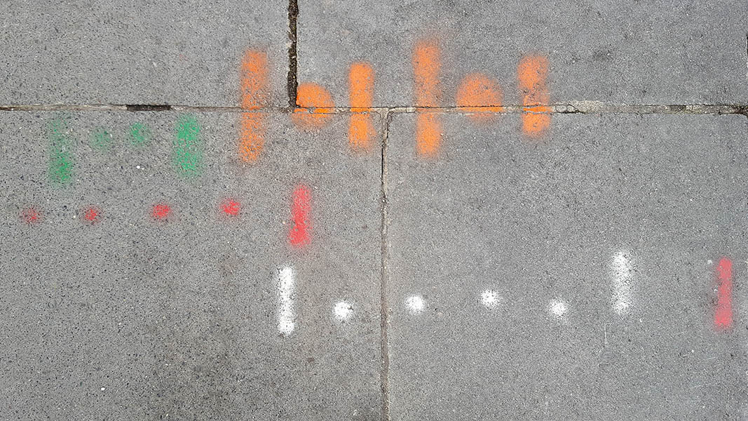 Pavement markings - spray painted squiggles on paving stones - Multiple groups of dots flanked by vertical lines in green, red, orange and white