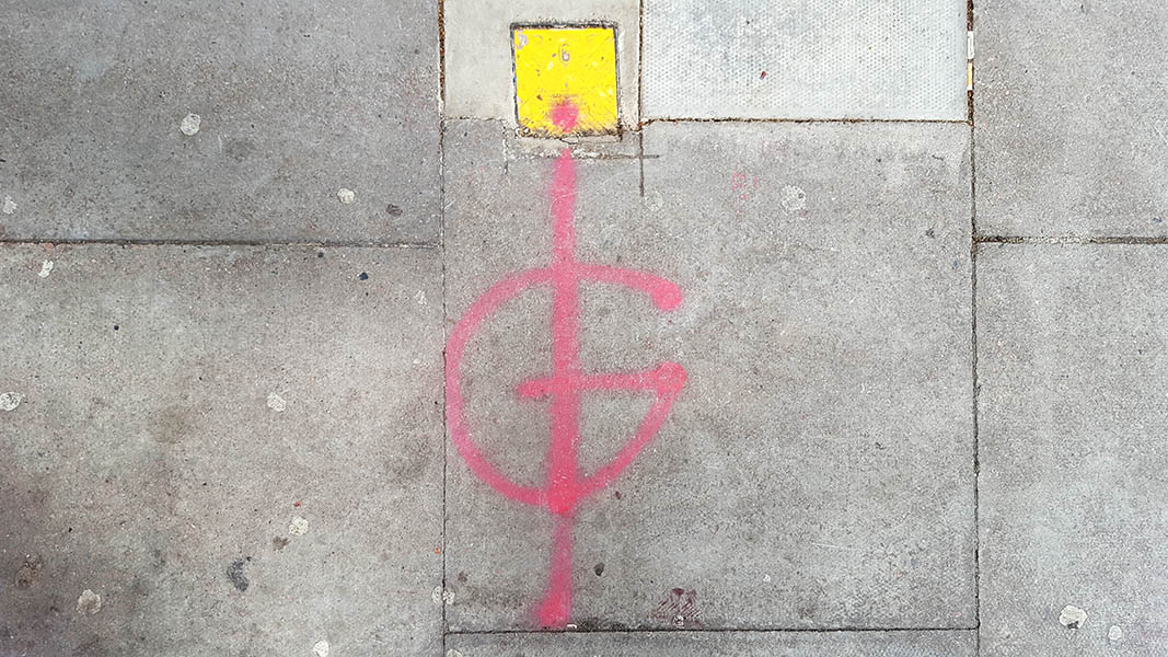 Pavement markings - spray painted squiggles on paving stones - Red G with vertical line through