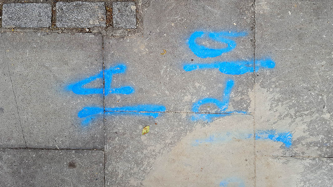 Pavement markings - spray painted squiggles on paving stones - Blue letters on pavement