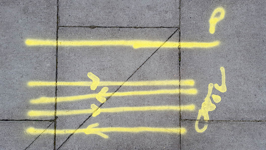 Pavement markings - spray painted squiggles on paving stones - Yellow lines with arrows and letters