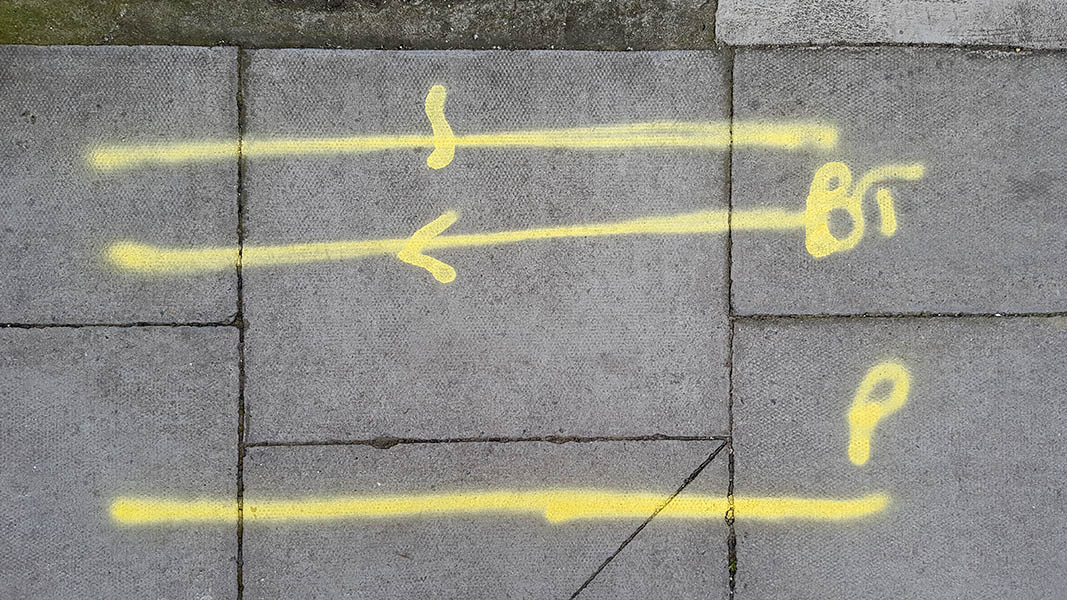 Pavement markings - spray painted squiggles on paving stones - Three yellow lines with arrows and letters