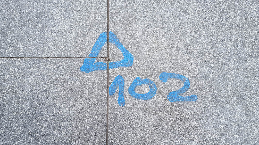 Pavement markings - spray painted squiggles on paving stones - Blue arrow above 102
