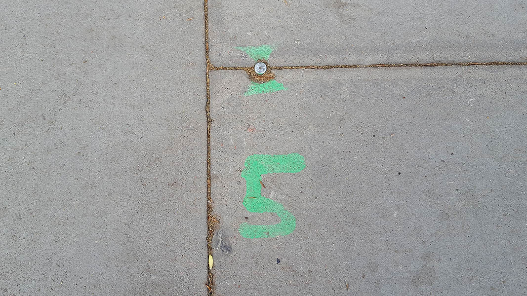Pavement markings - spray painted squiggles on paving stones - Green arrows above 5