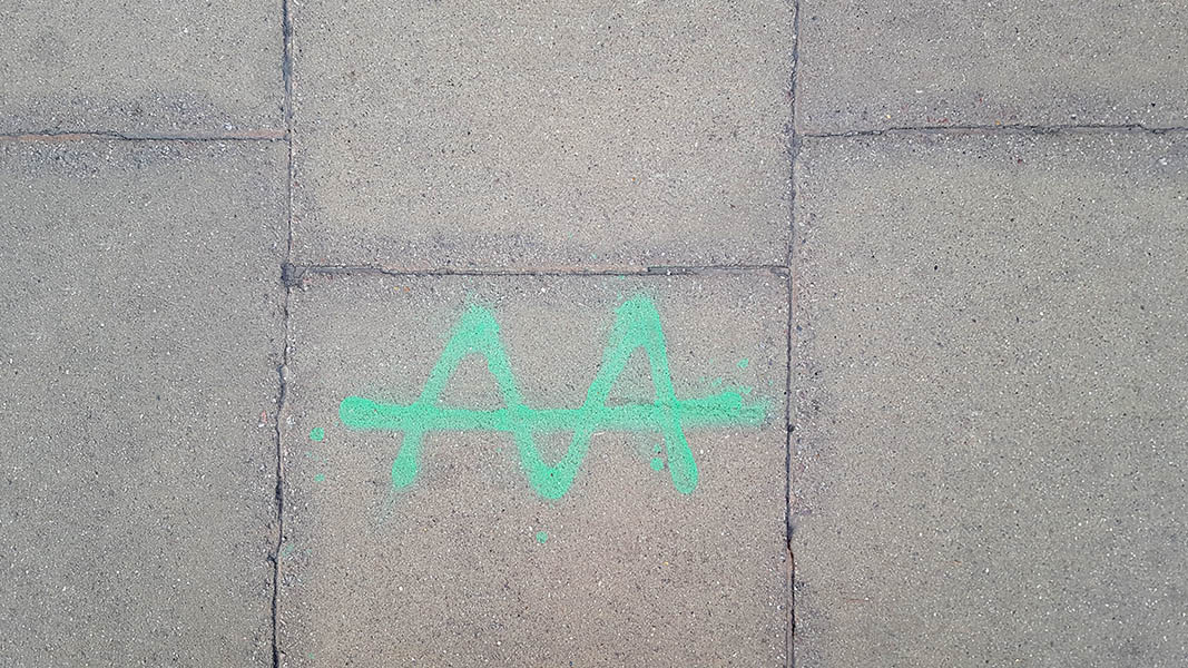 Pavement markings - spray painted squiggles on paving stones - Green crossed through zig zag