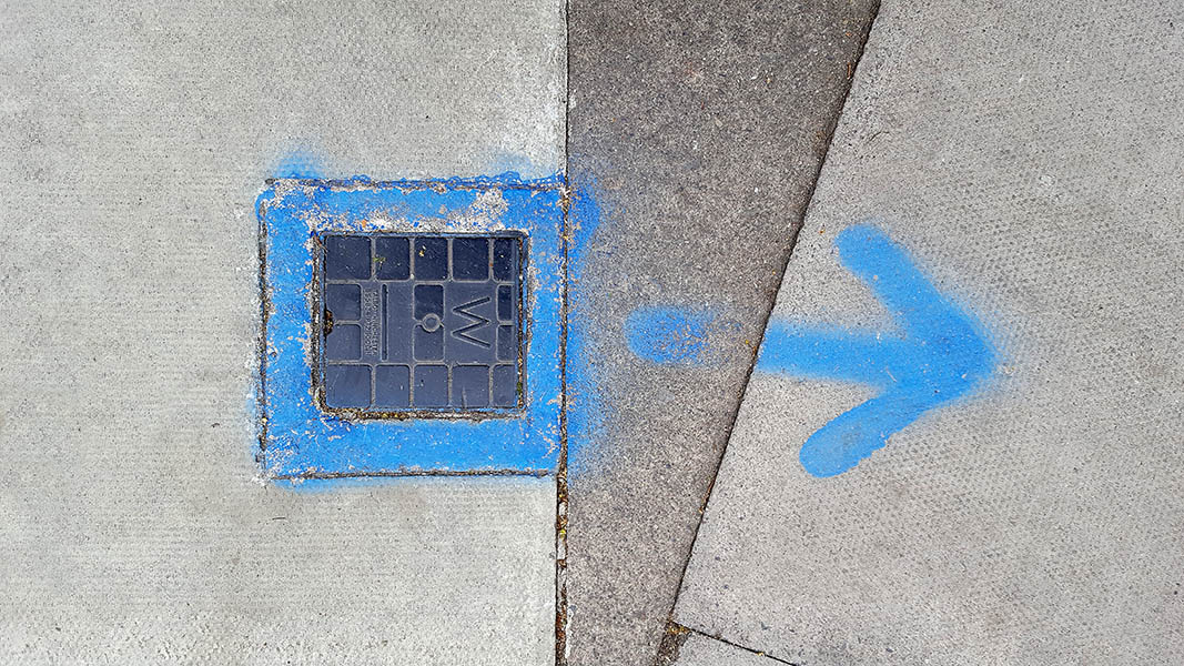 Pavement markings - spray painted squiggles on paving stones - Blue square with arrow