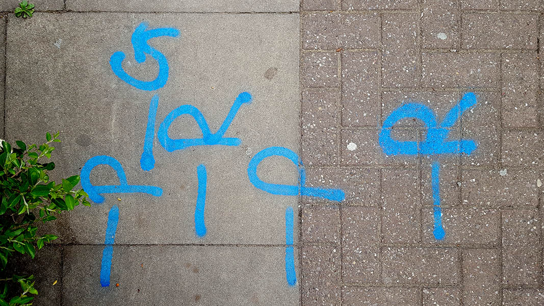 Pavement markings - spray painted squiggles on paving stones - Blue lines and writing