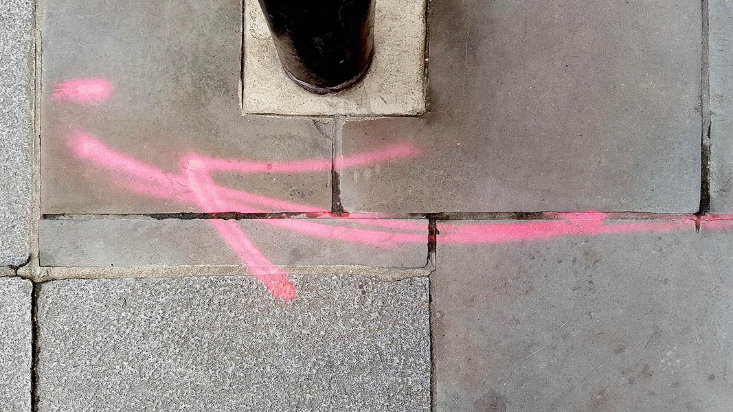Pavement markings - spray painted squiggles on paving stones - Red curved arrow