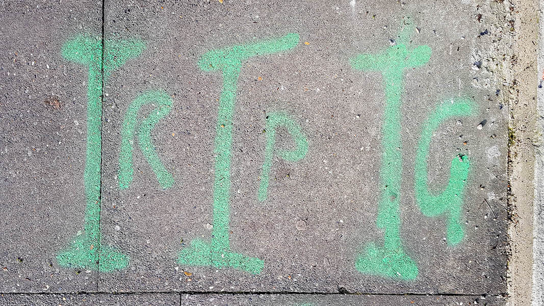Pavement markings - spray painted squiggles on paving stones - Green vertical lines and the letters RPG