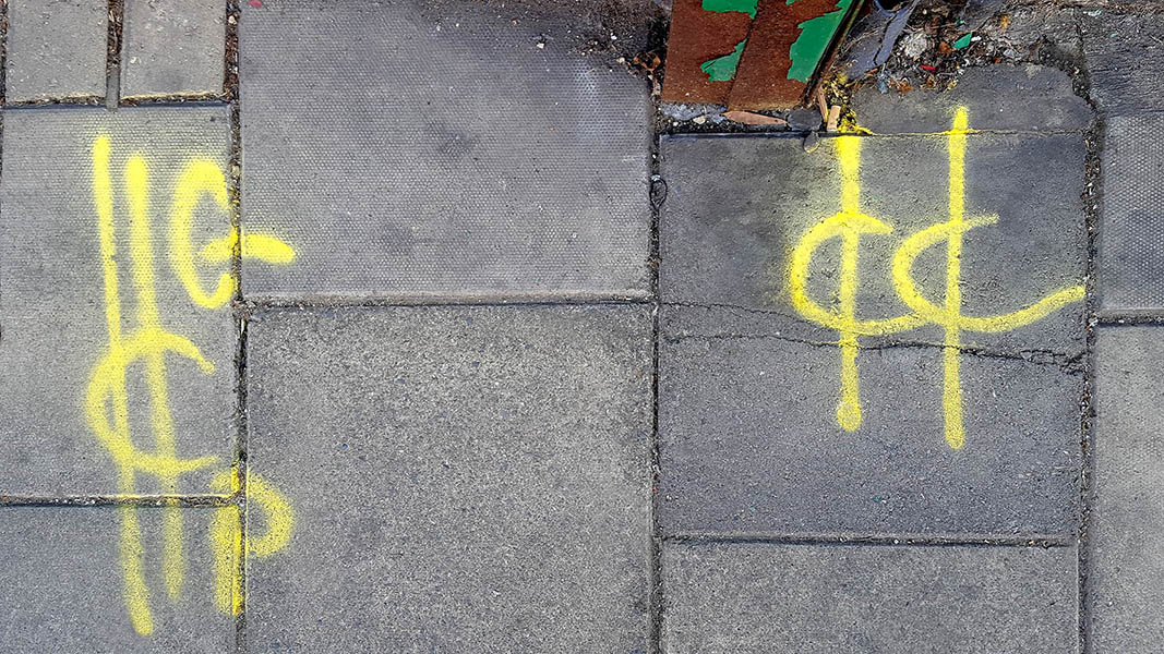 Pavement markings - spray painted squiggles on paving stones - Yellow vertical lines and letters