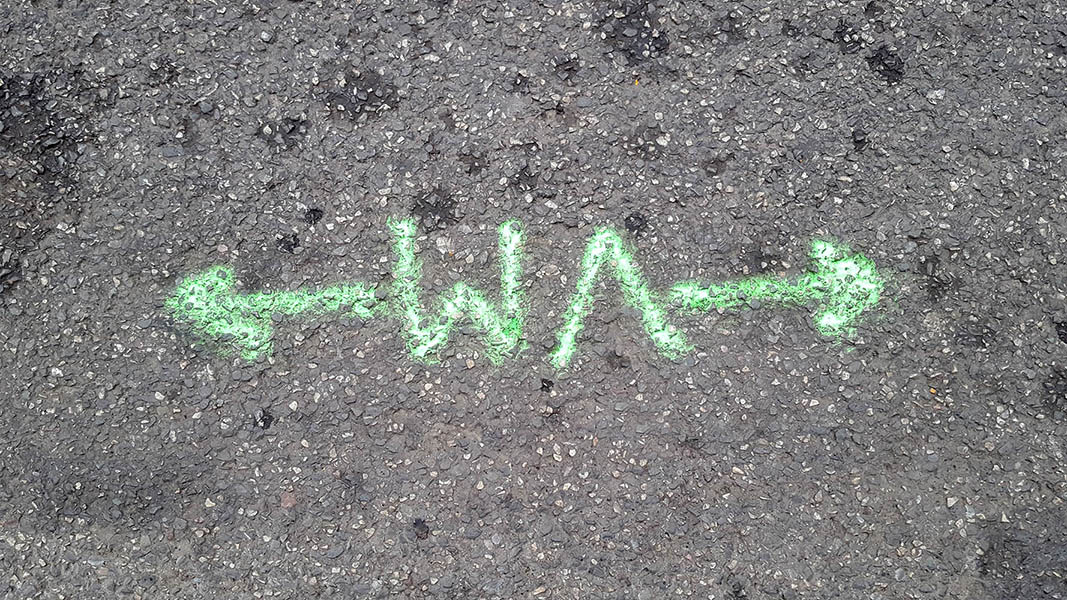 Pavement markings - spray painted squiggles on tarmac - Green horizontal arrows and the letters WA