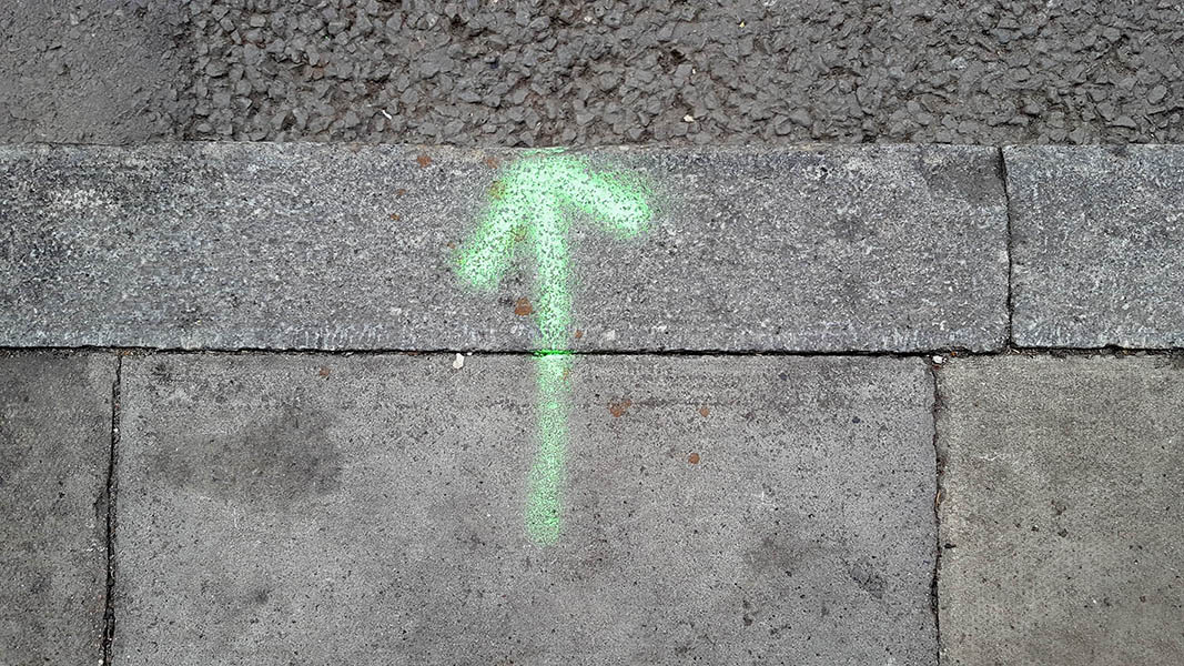 Pavement markings - spray painted squiggles on paving stones - Green vertical arrow