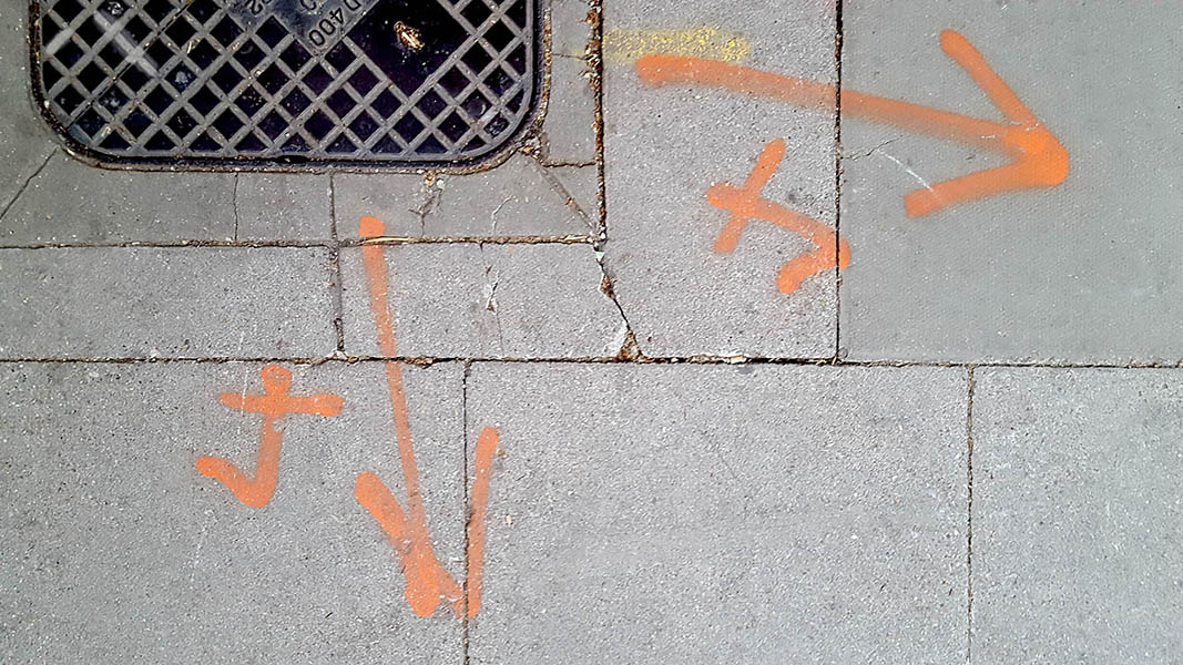 Pavement markings - spray painted squiggles on paving stones - 2x orange arrowsand 2x orange 4 